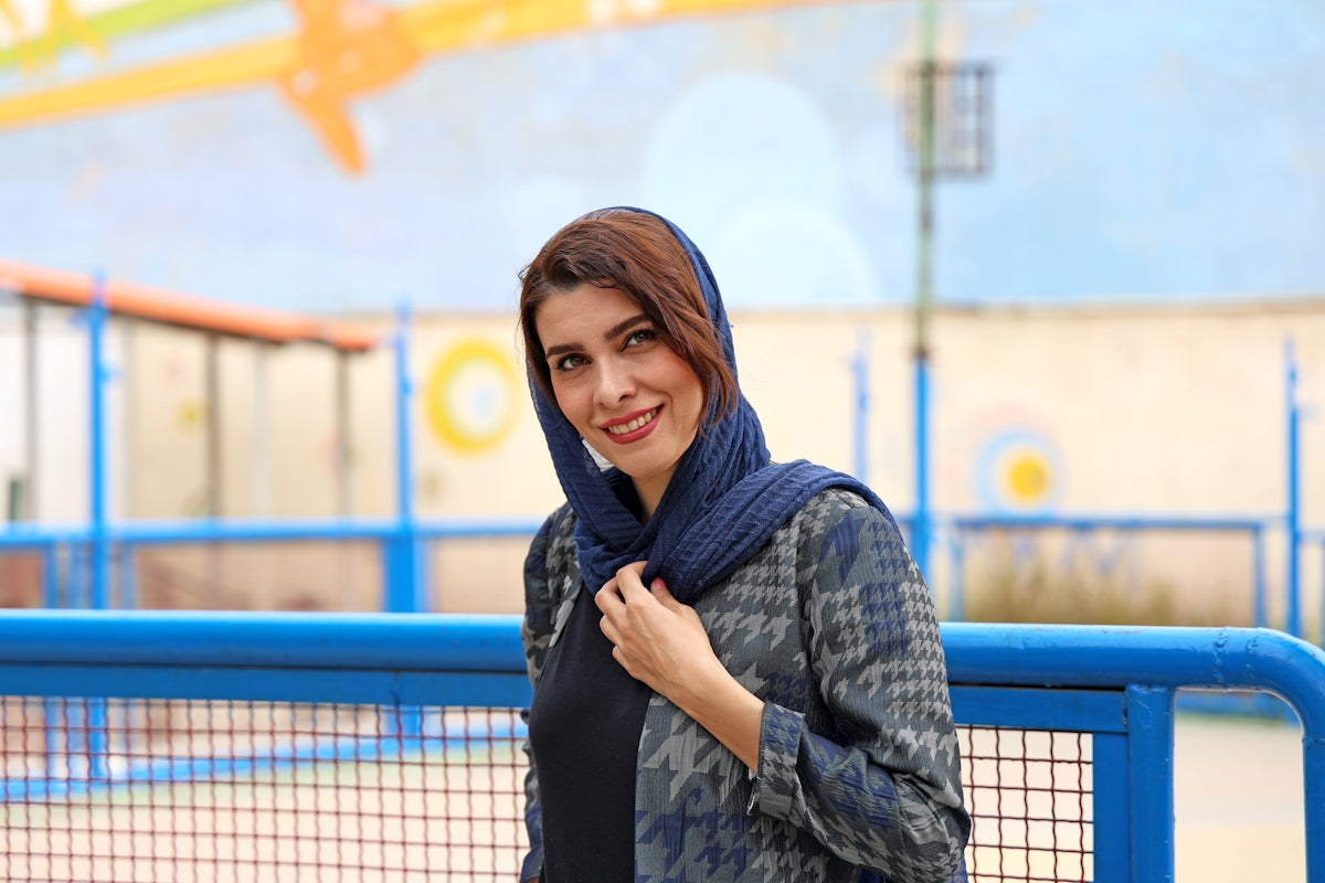A woman wearing a headscarf smiles outdoors.